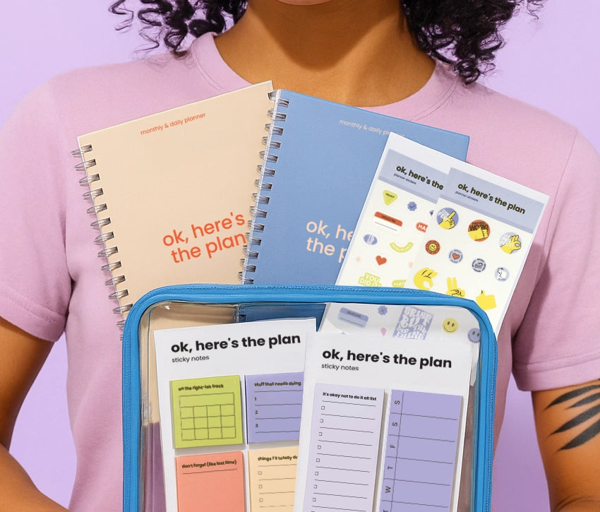 Person holding a set of colorful Toffu Store planners against a purple background