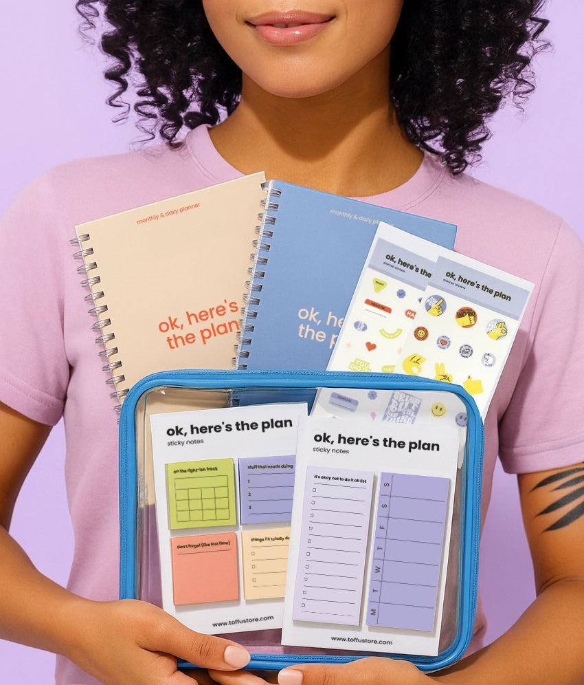 Person holding a set of colorful Toffu Store planners against a purple background