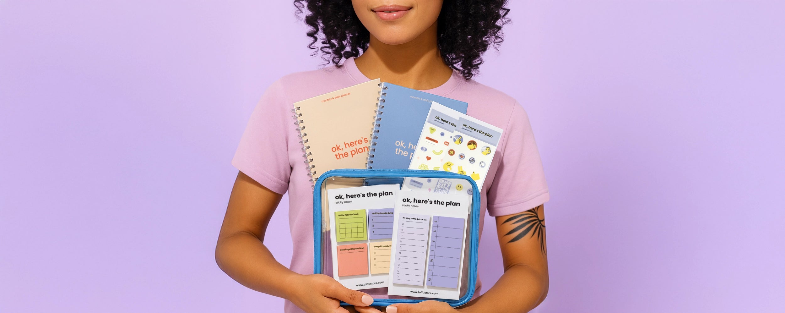 Person holding a set of colorful Toffu Store planners against a purple background